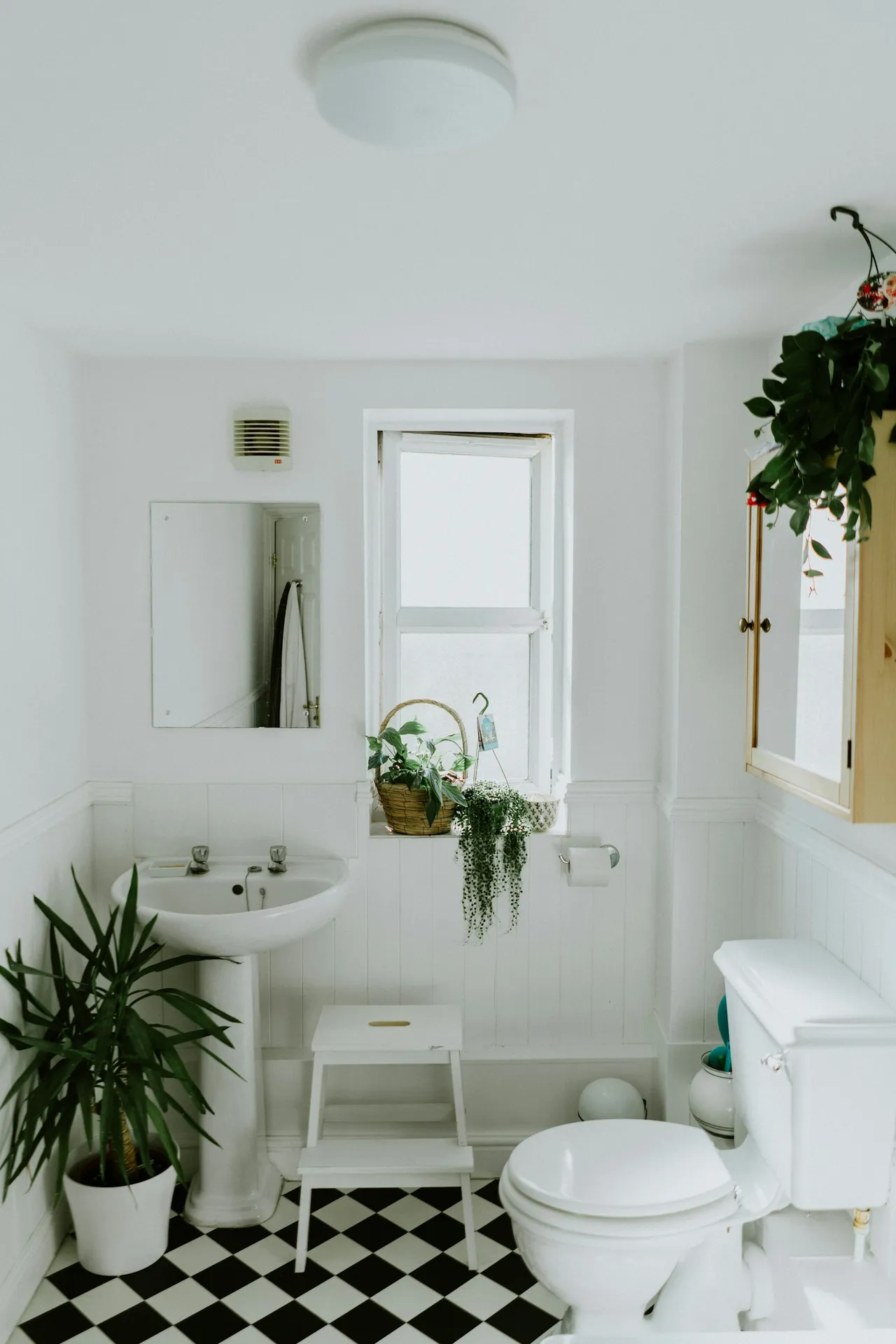 Residential bathroom with a pedestal sink, toilet, and exhaust grille
