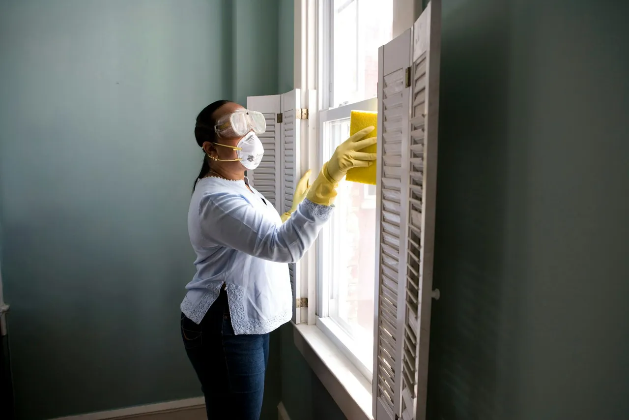 A person wiping an interior window during a rental make-ready