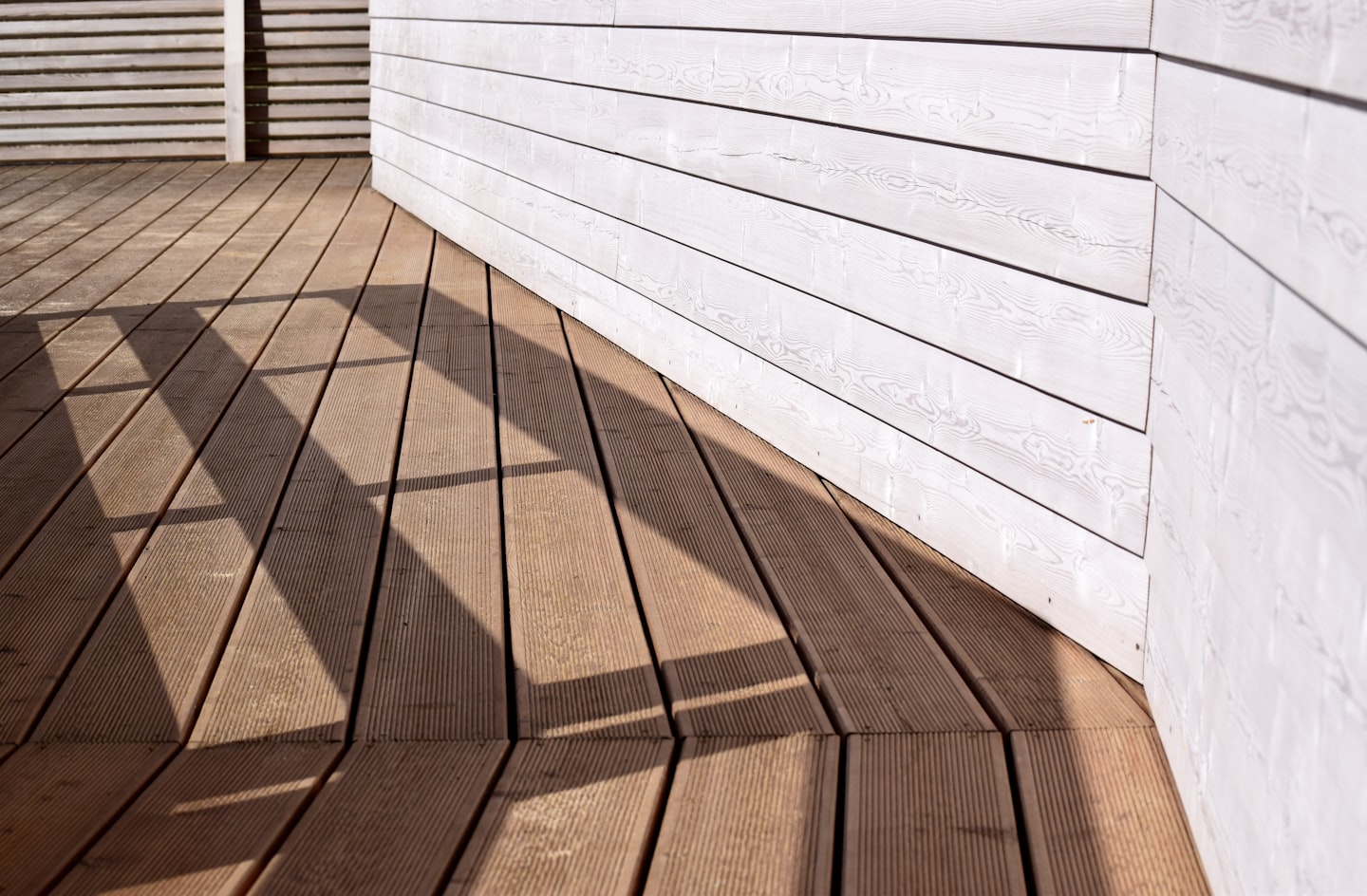 Wooden deck boards meeting painted white siding
