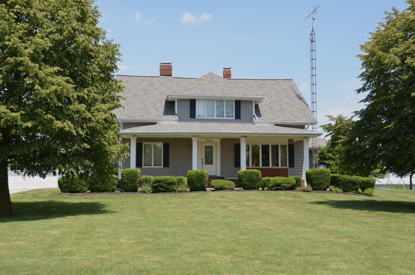 A two-storey house with a covered porch and a mown front lawn