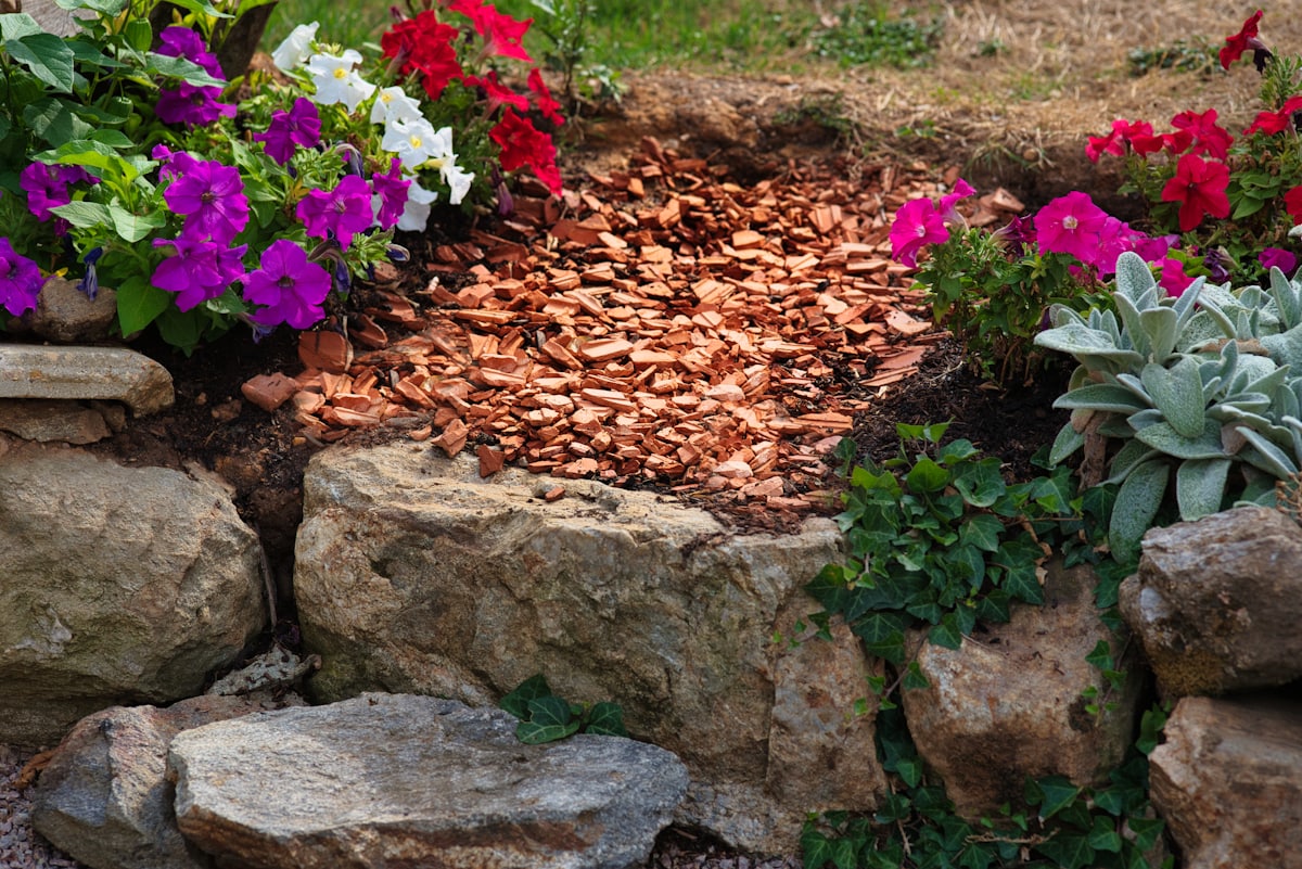 Fresh bark mulch spread through a planted bed edged with stone
