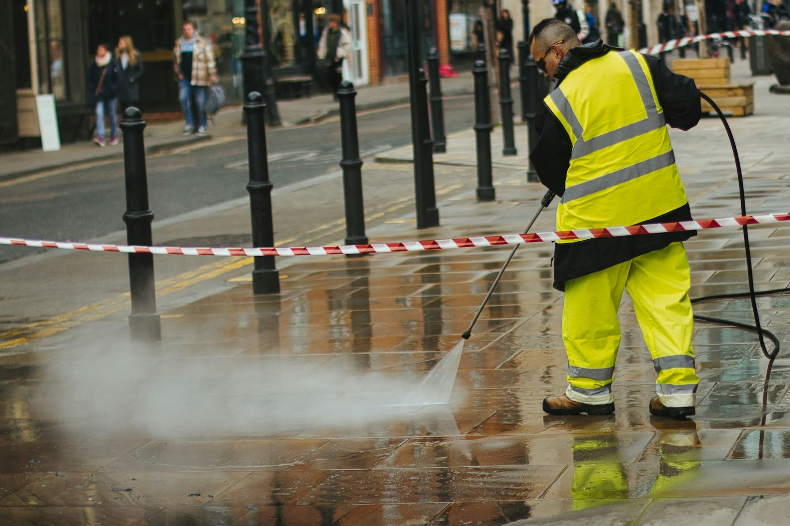 A pressure washer rinsing a paved walkway
